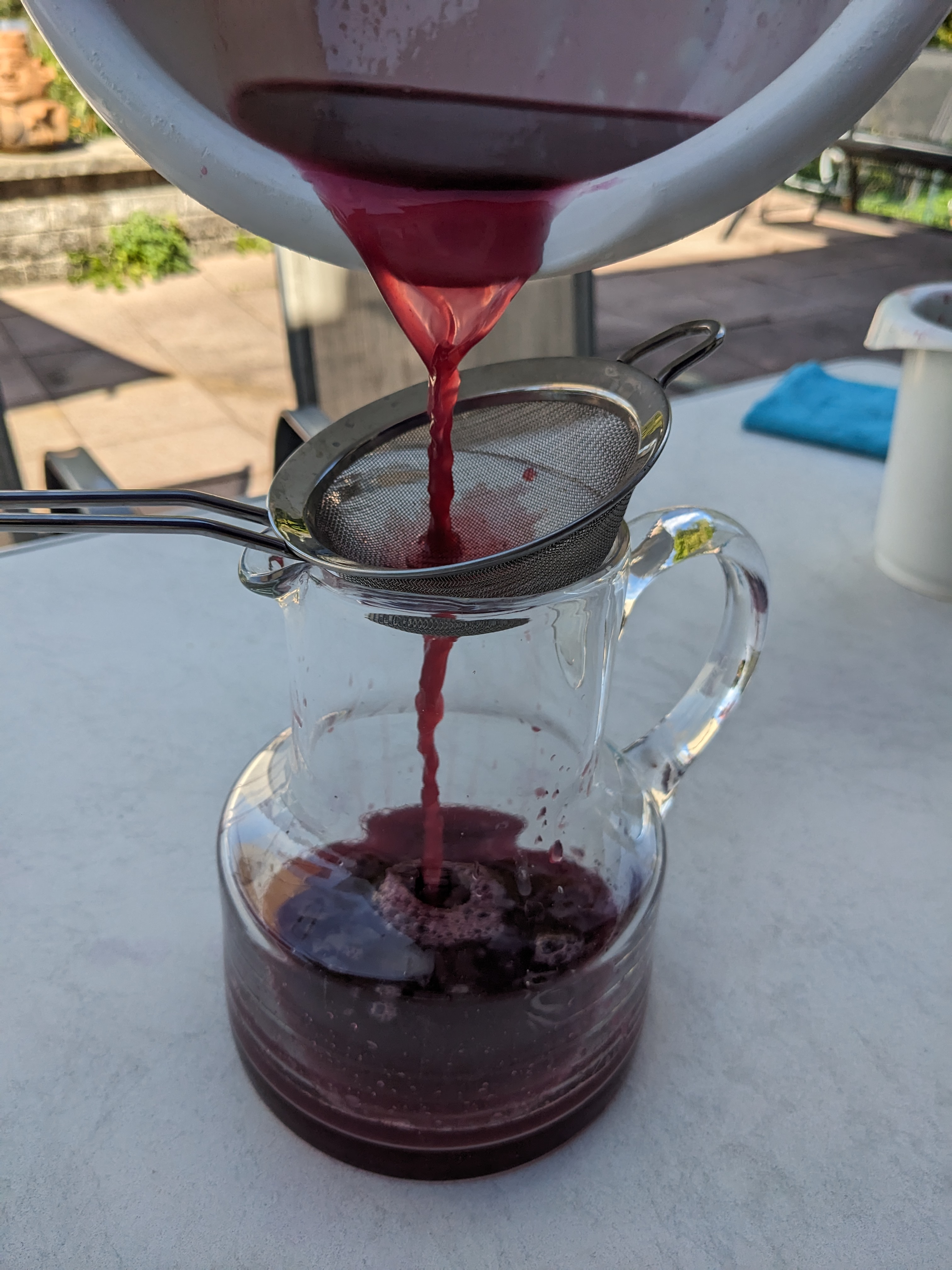 Pouring the juice through a finer sieve into a glass jug.