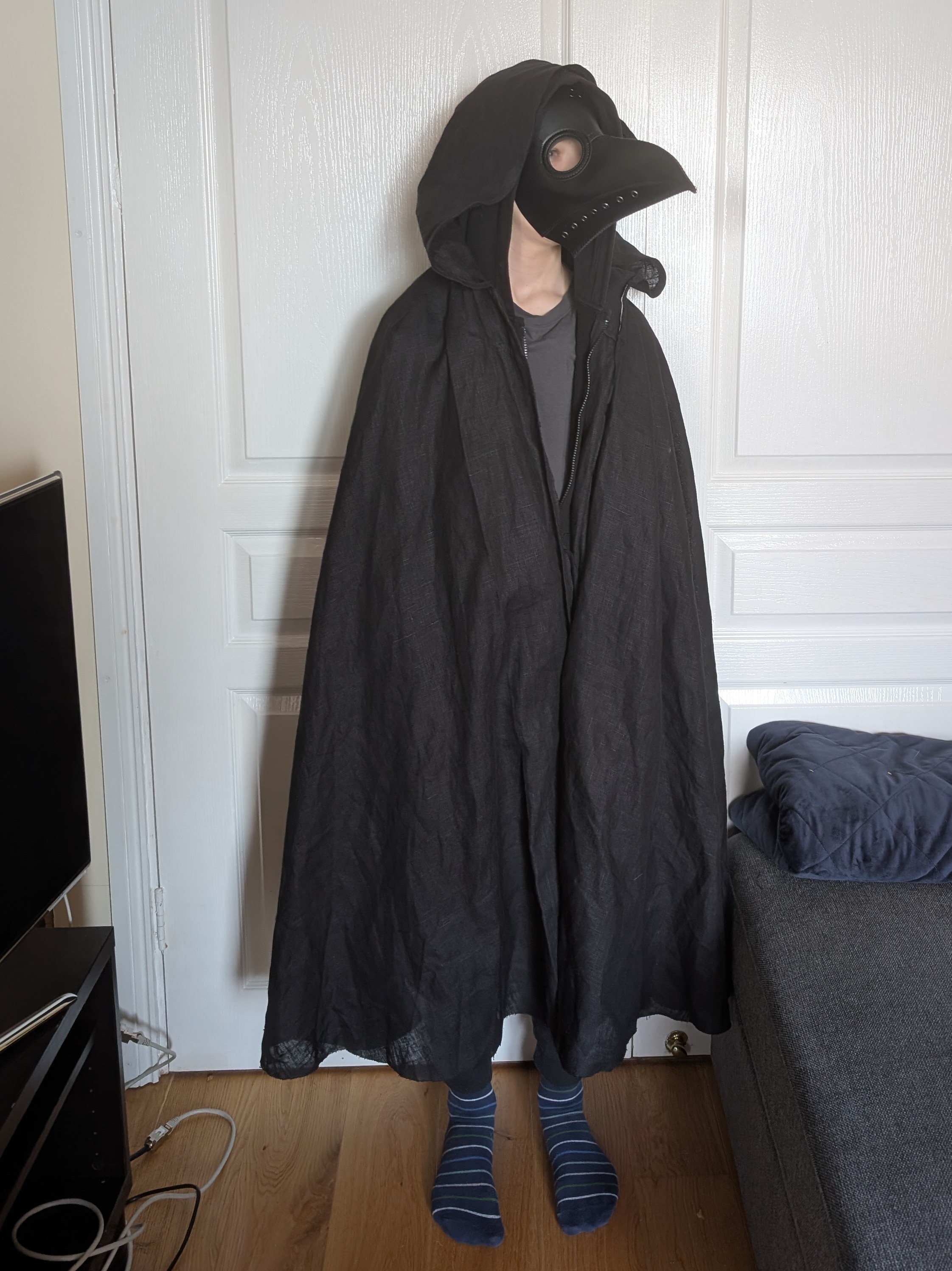 Photo of a child wearing a beaked 'plague doctor' mask and a black cloak